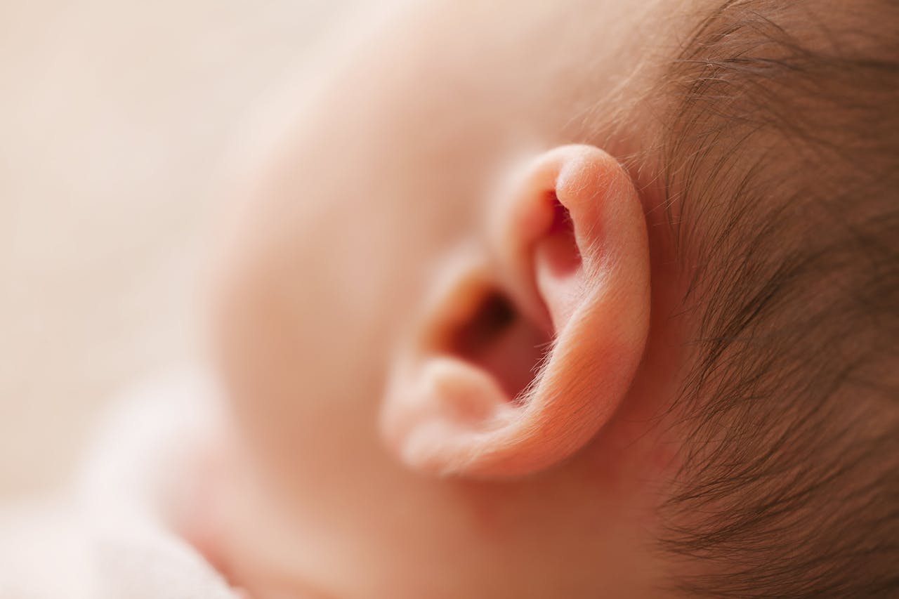 about-01 Gentle close-up of a newborn baby's ear, showcasing delicate features in a soft focus image.